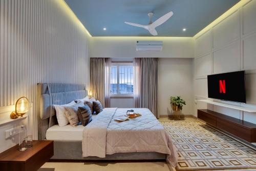 a bedroom with a large bed and a tv at ELIVAAS Shourya Bliss Lux 3BHK Villa with Pvt Pool, Udaipur in Udaipur