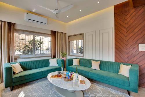 a living room with a green couch and a table at ELIVAAS Shourya Bliss Lux 3BHK Villa with Pvt Pool, Udaipur in Udaipur