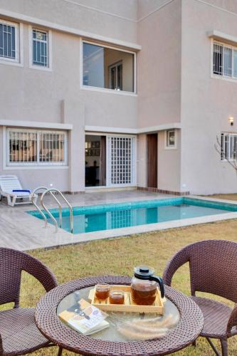 a table with a tray of food on it next to a swimming pool at ELIVAAS Shourya Bliss Lux 3BHK Villa with Pvt Pool, Udaipur in Udaipur