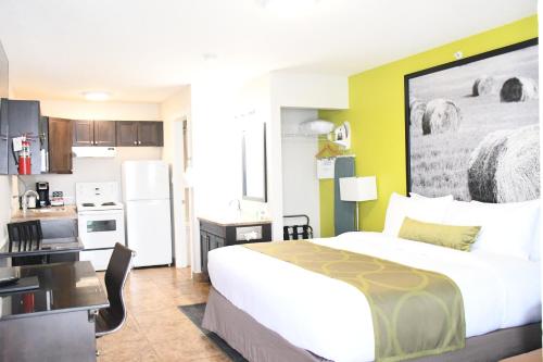 a bedroom with a large bed and a kitchen at Super 8 by Wyndham Fort McMurray in Fort McMurray
