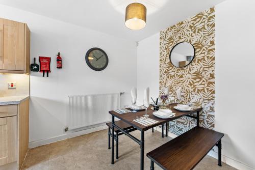 a dining room with a table and a clock on a wall at Stunning Manchester House - Garden in Manchester