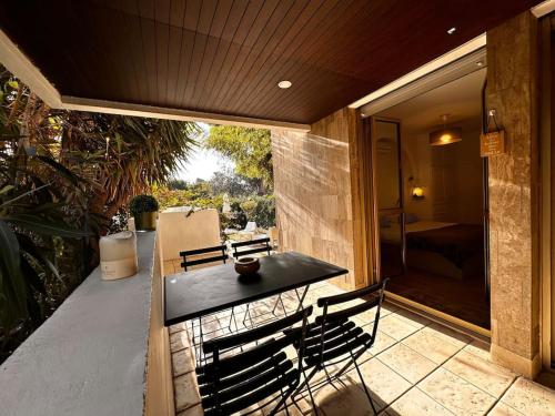 une terrasse couverte avec une table noire et des chaises. dans l'établissement Charmant appartement Proche plage 4P avec jardin, à Marseille
