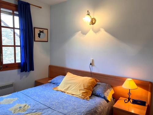 a bedroom with a bed and a lamp and a window at Rústic de Llavorsí - L'Amfitriona in Llavorsí