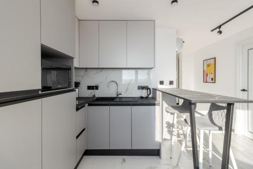 a kitchen with white cabinets and a table with a sink at 77 views apartments by INSHI in Lviv