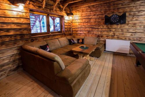 a living room with a couch and a table in a log cabin at Domek całoroczny RYSIÓWKA na Kaszubach z basenem banią sauną bilardem na wyłączność - Ostrowite Leśna Dolina in Sulęczyno