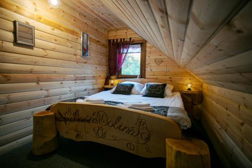 a bedroom with a bed in a log cabin at Domek całoroczny RYSIÓWKA na Kaszubach z basenem banią sauną bilardem na wyłączność - Ostrowite Leśna Dolina in Sulęczyno