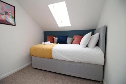 a bedroom with a bed with colorful pillows at Summerlays 2 BR apartment in the centre of Bath in Bath