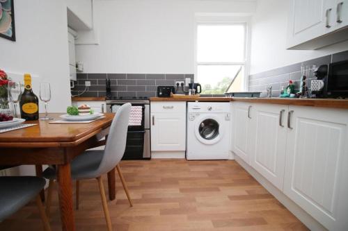 a kitchen with a table and a washing machine at Summerlays 2 BR apartment in the centre of Bath in Bath
