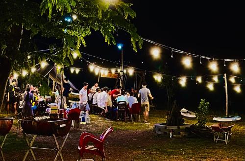 a group of people sitting at a party under lights at The Secret Garden Camping - Hồ Trị An 