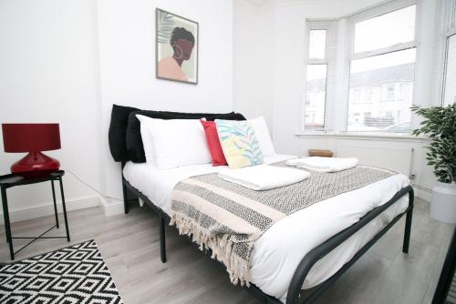 una camera da letto con un letto con cuscini bianchi e rossi di Malpas House 4 BR Free street parking a Newport