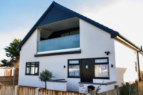uma casa branca com uma grande janela de vidro em The Beach House with Balcony North Wales em Kinmel Bay