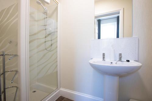 a white bathroom with a sink and a shower at Cosy Flat in Victorian Villa- Parking & Garden in Torquay