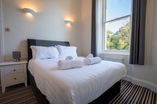 um quarto com uma cama grande e toalhas em Cosy Flat in Victorian Villa- Parking & Garden em Torquay