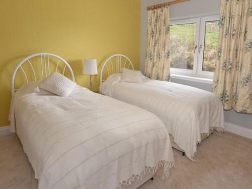 two white beds in a room with a window at Glen View Lodge in Inverness
