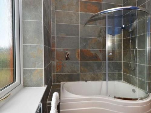 La salle de bains est pourvue d'une baignoire et d'une douche. dans l'établissement Glen View Lodge, à Inverness