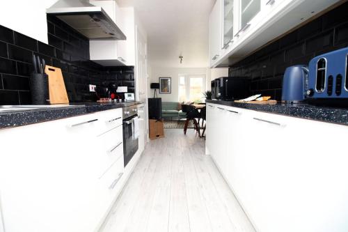 eine Küche mit schwarzen Wänden, weißen Schränken und weißem Boden in der Unterkunft 4 BR with FREE on street parking in Bristol