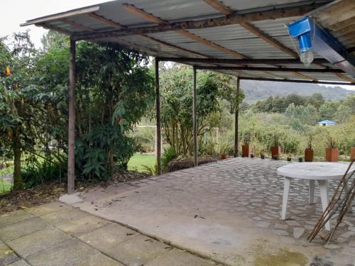 a pavilion with a white table and a chair at Acogedora cabaña entre las montañas de La Calera- Colombia in La Calera