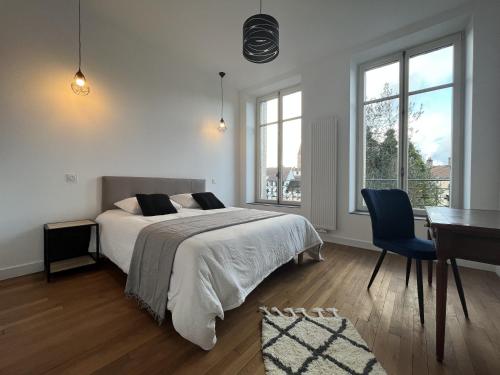 a bedroom with a bed and a desk and windows at L'aristide in Épinal