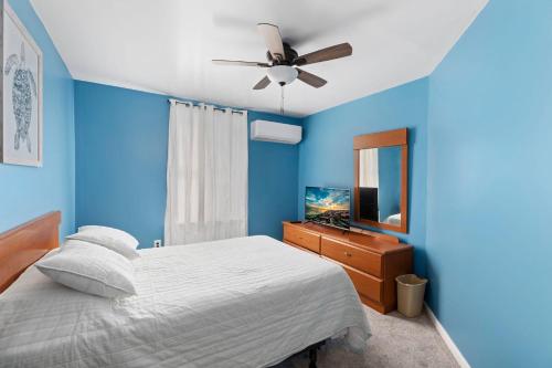 a blue bedroom with a bed and a ceiling fan at Unit 2 at The Sunflower in Wildwood in Wildwood