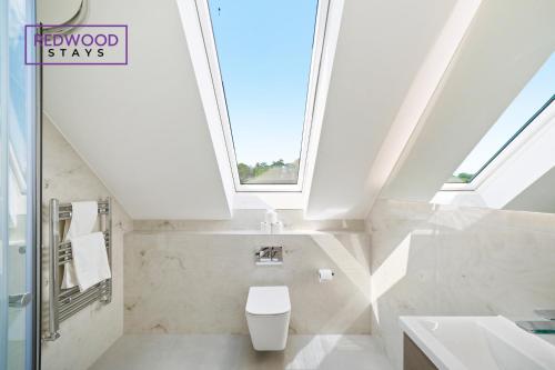 uma casa de banho com um WC e uma janela em BRAND NEW! Modern Houses For Contractors & Families with FREE PARKING, FREE WiFi & Netflix By REDWOOD STAYS em Farnborough