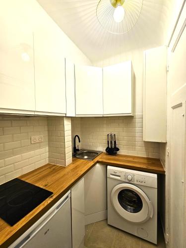 une cuisine avec des armoires blanches et une machine à laver dans l'établissement Comme une suite près du métro, à Clichy