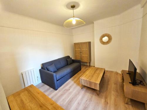 un salon avec un canapé bleu et une table dans l'établissement Comme une suite près du métro, à Clichy