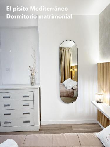 a bedroom with a white dresser and a mirror at El pisito mediterráneo in Melilla