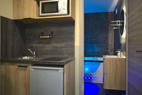 eine Küche mit einer Spüle und einer Mikrowelle in der Unterkunft Littleparadise jacuzzi à 5 minutes du centre ville in Mulhouse