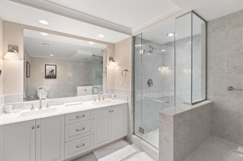 a bathroom with two sinks and a shower with a glass door at Luxury Living at The Grand in Wildwood