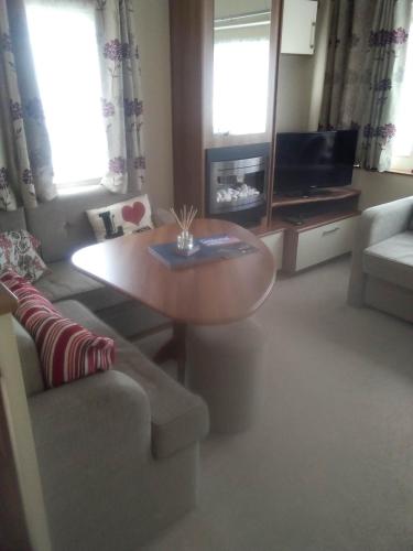 a living room with a table and a couch at New Forest Caravan, #108 in New Milton