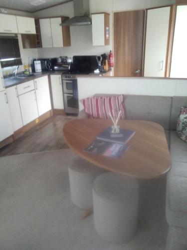 a kitchen with a wooden table with stools in it at New Forest Caravan, #108 in New Milton