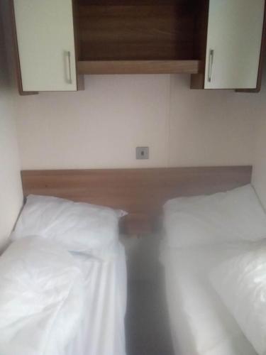 two beds in a room with white sheets and cabinets at New Forest Caravan, #108 in New Milton
