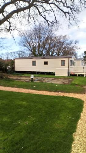 a large white building with a tree in the foreground at New Forest Caravan, #108 in New Milton