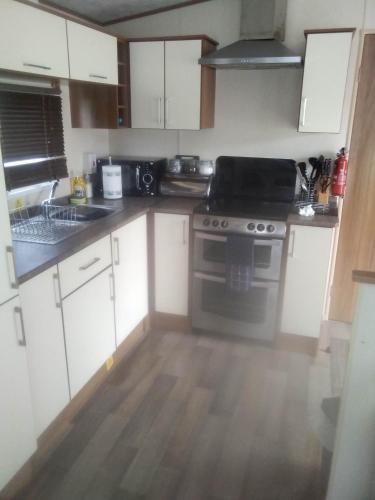 a kitchen with white cabinets and a stove top oven at New Forest Caravan, #108 in New Milton