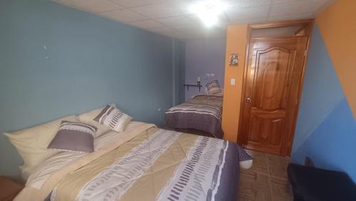 - une chambre avec 2 lits dans une pièce aux murs bleus dans l'établissement LULU HOUSE, à Machachi