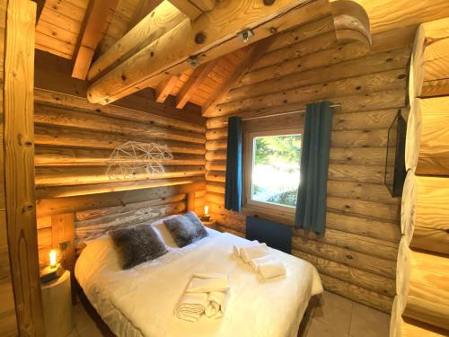 ein Schlafzimmer mit einem Bett in einem Blockhaus in der Unterkunft L'OURSBLANC Chalet en rondins in La Bresse