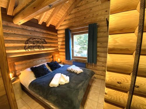 une chambre avec un lit dans une cabane en rondins dans l'établissement L'OURS NOIR Chalet en rondins, à La Bresse