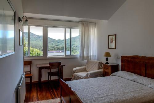 a bedroom with a bed and a chair and a window at Casa Rural O Pozo in Borela