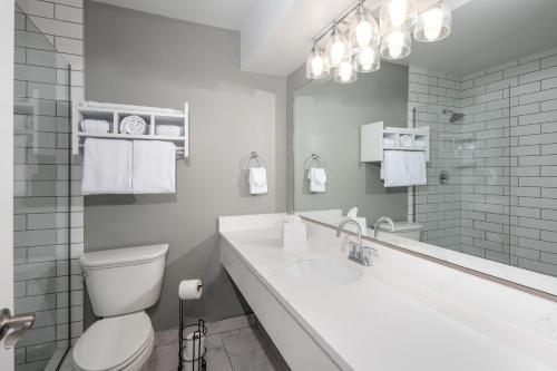 a white bathroom with a toilet and a sink at Tides Folly Beach in Folly Beach