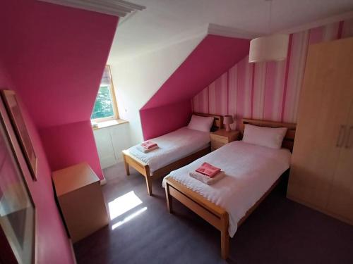 a pink room with two beds and a window at 4 bedroom / 2 bathroom house in desirable area. in Dundee