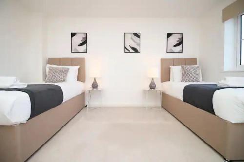 Duas camas num quarto branco com preto e branco em Seymour Way Stunning 4 bed with FREE parking em Magor
