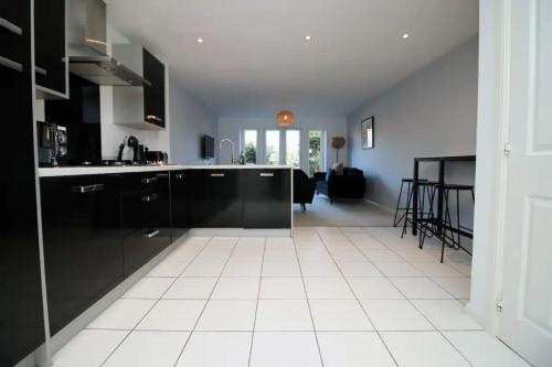 a kitchen with black cabinets and a white tile floor at Seymour Way Stunning 4 bed with FREE parking in Magor