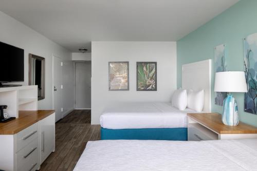 a hotel room with two beds and a flat screen tv at Tides Folly Beach, Charleston's Oceanfront Hotel in Folly Beach