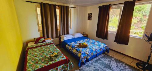 1 dormitorio con 2 camas y 2 ventanas en Akivai Lodge Ua-Pou, en Hakamui