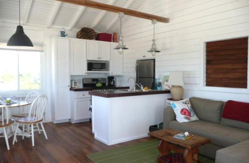 a living room and kitchen with a couch and a table at Barbuda Cottages in Codrington Village