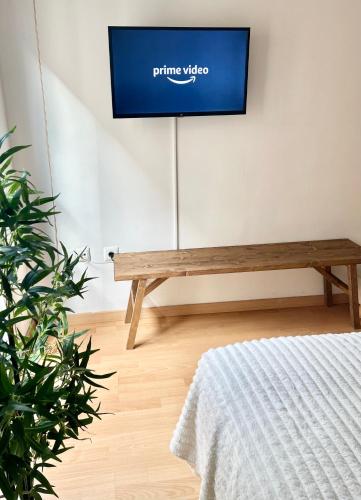 - une télévision dans une chambre avec un banc en bois dans l'établissement Apartment Rosario in Malaga center, à Malaga