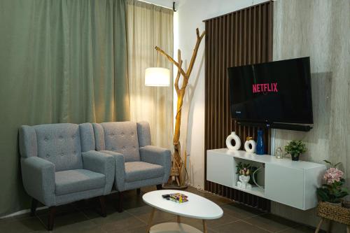 een woonkamer met 2 stoelen en een televisie bij Casa Valencia 6 in Santa Elena