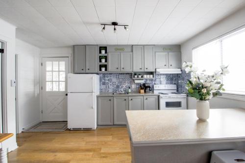 a kitchen with white appliances and a white refrigerator at Repère d'Eastman - Spa et Foyer au bois in Eastman