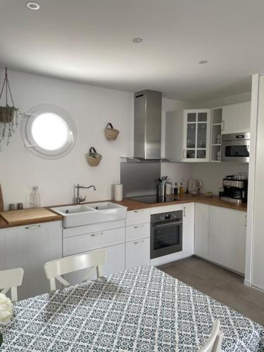 uma cozinha com armários brancos, uma mesa e um lavatório em Les Lodges de Saint Brice 1 em Arès