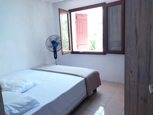 a bedroom with a bed and a window and a fan at Oasis Appartement in Blue Bay